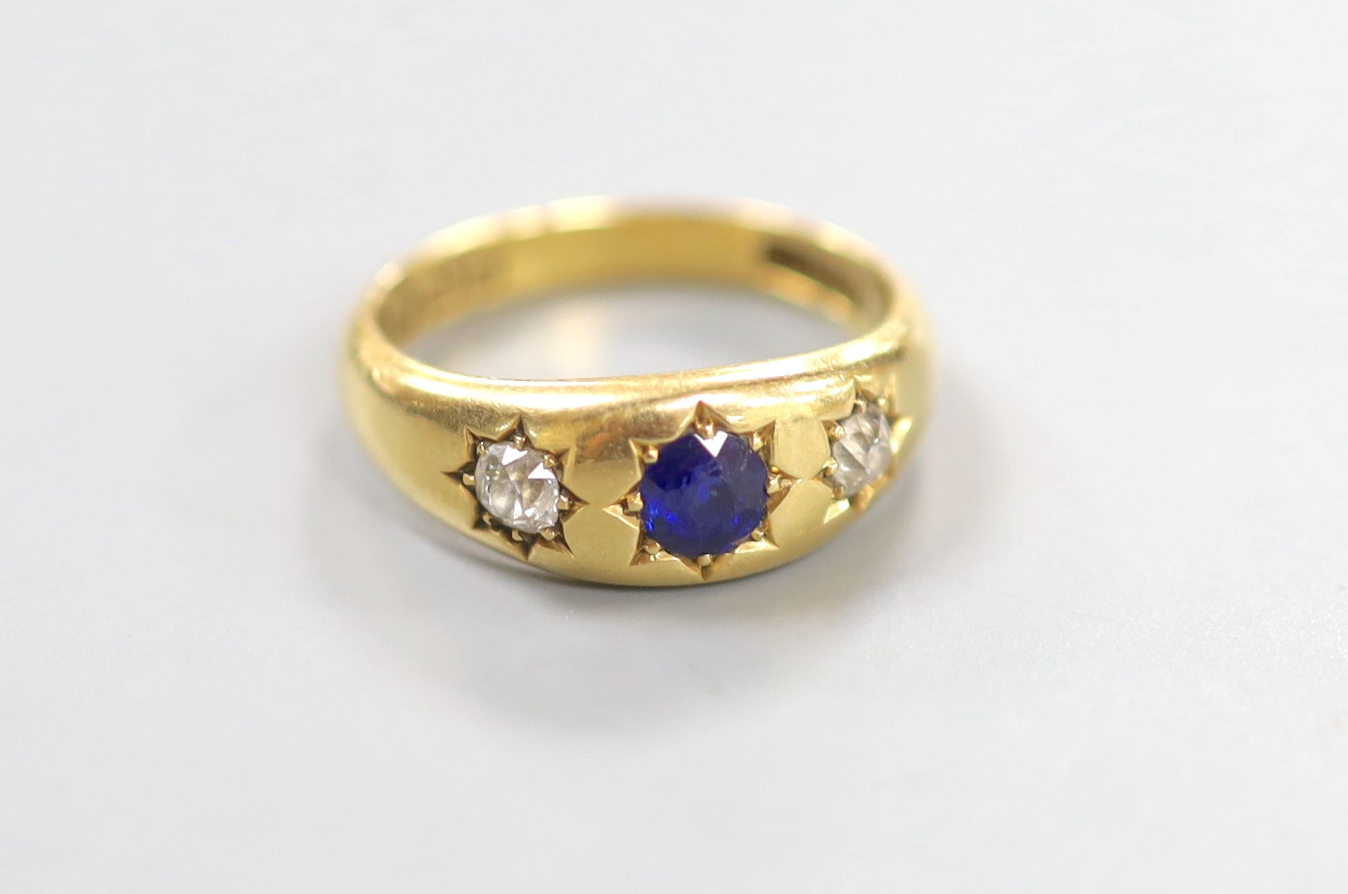 A late Victorian 18ct gold and gypsy set sapphire and diamond three stone ring, size N, gross 5.8