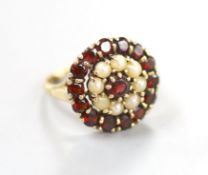 A modern 9ct gold, garnet and split pearl set circular cluster ring, size M, 5 grams.