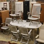 A weathered teak extending garden table, diameter 128cm, height 68cm and six folding elbow chairs