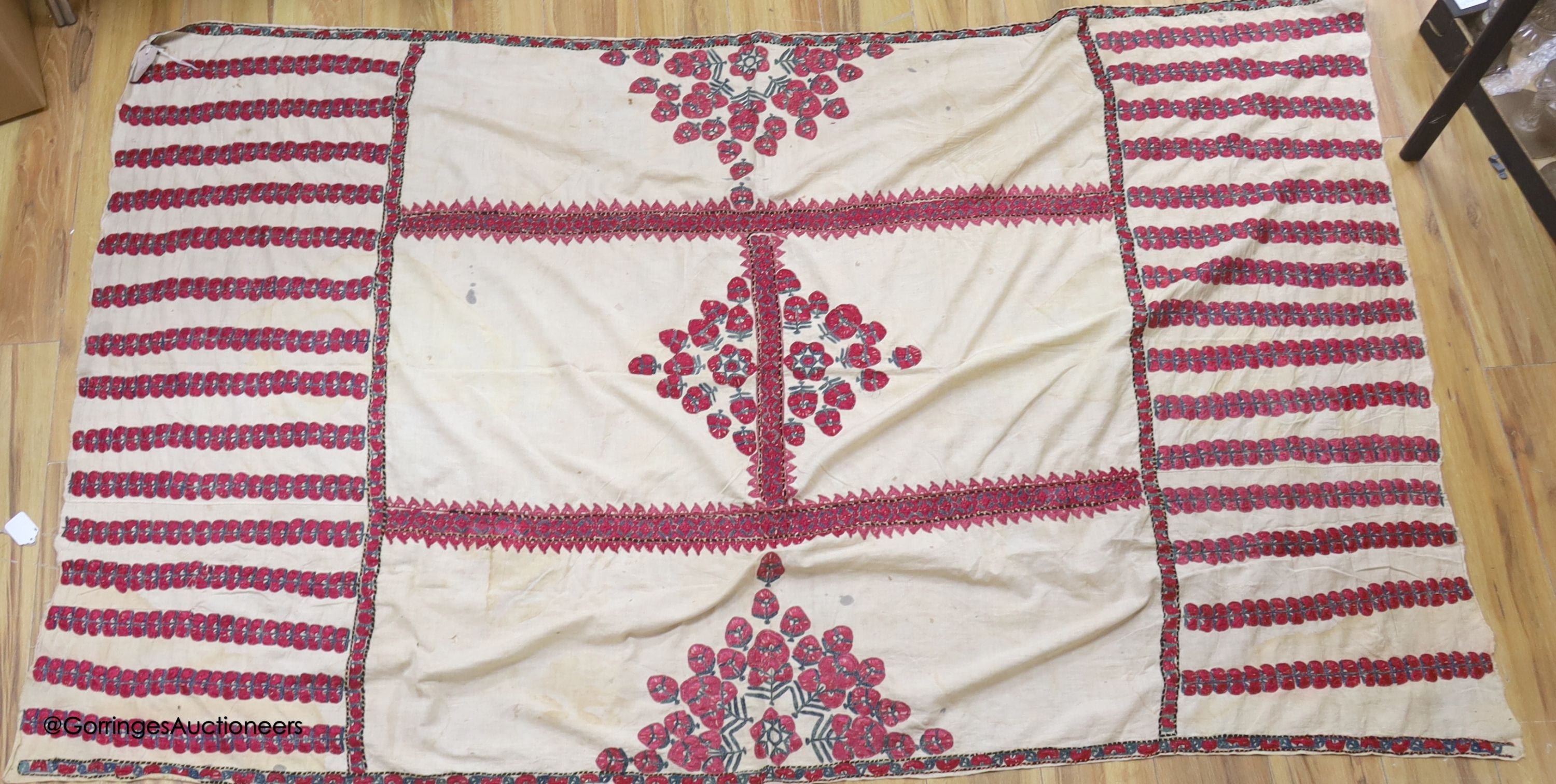 A silk embroidered Suzani, embroidered with cherry red flower heads with green stems and leaves in