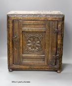 A small 17th century carved oak wall cabinet, enclosed by single panelled door with iron butterfly