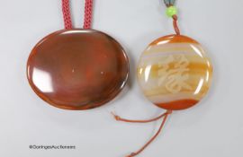 Two agate pendants, on fabric cords, largest pendant 57mm.