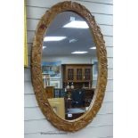 A carved oak oval framed wall mirror, width 70cm, height 109cm