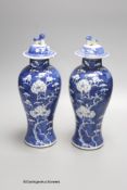 A pair of early 20th century Chinese blue and white prunus vases and covers, height 30cm