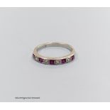 And 18 carat white gold ruby and diamond half eternity ring, size O, gross 2.7g.