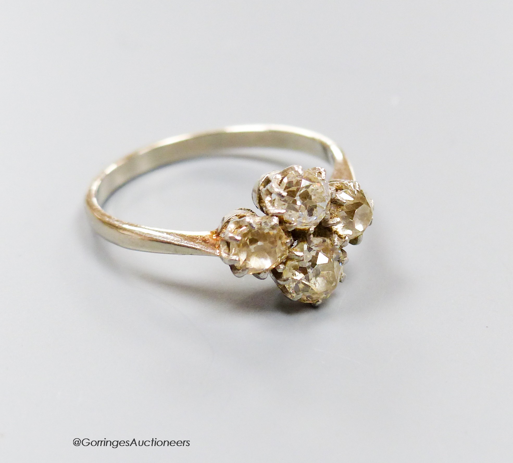 A white metal (stamped plat) and four stone diamond cluster ring, size O/P, gross 3.3 grams.