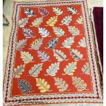 A red ground multi-coloured flat weave woollen rug with leaf decoration. 161 x 126cm.