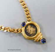 A modern curb link yellow metal, inset coin, blue cabochon stone and diamond set pendant necklace,