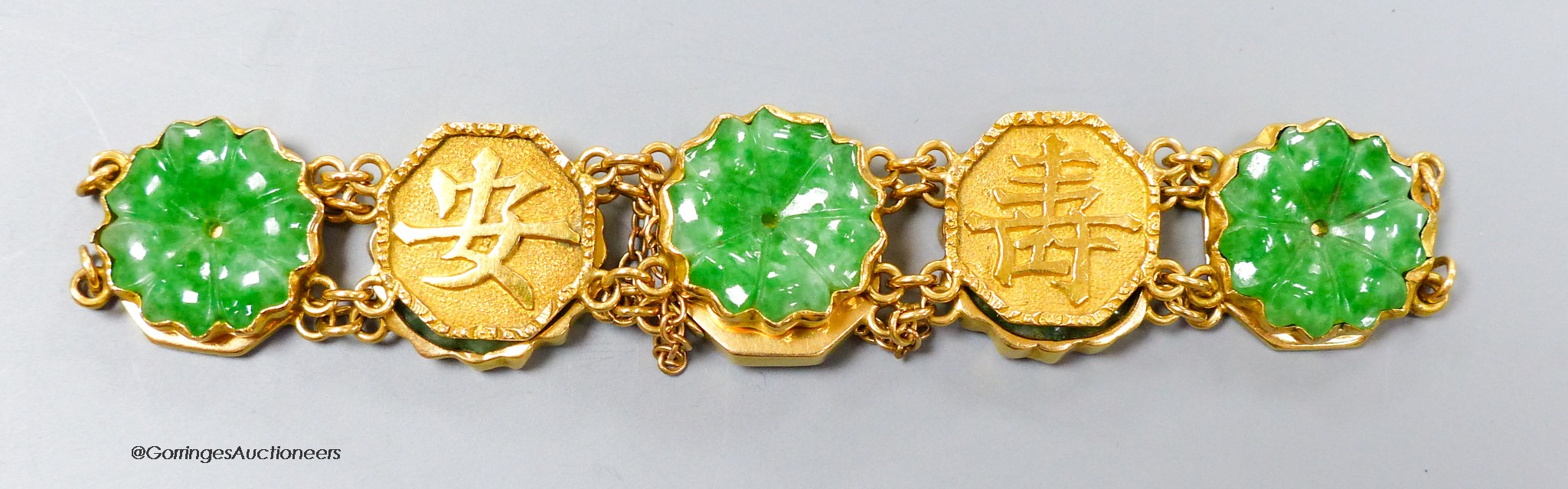 A Chinese yellow metal (stamped WH 20) and carved jadeite disc set bracelet, 18cm, gross 19 grams.