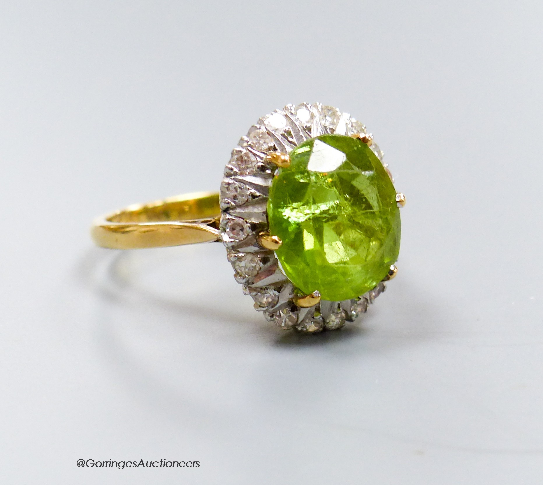 An 18ct, peridot and diamond oval cluster set dress ring, size T, gross 7 grams.