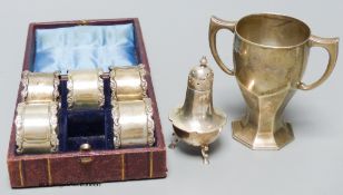 A Mappin & Webb small silver trophy cup, a silver pepperette and five cased silver napkin rings.