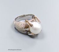 A modern white metal (stamped 750) and claw set cultured pearl dress ring, with pave diamond set