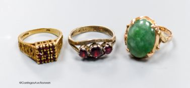 A 9ct gold and garnet cluster ring, a similar white metal ring and a yellow metal and jadeite