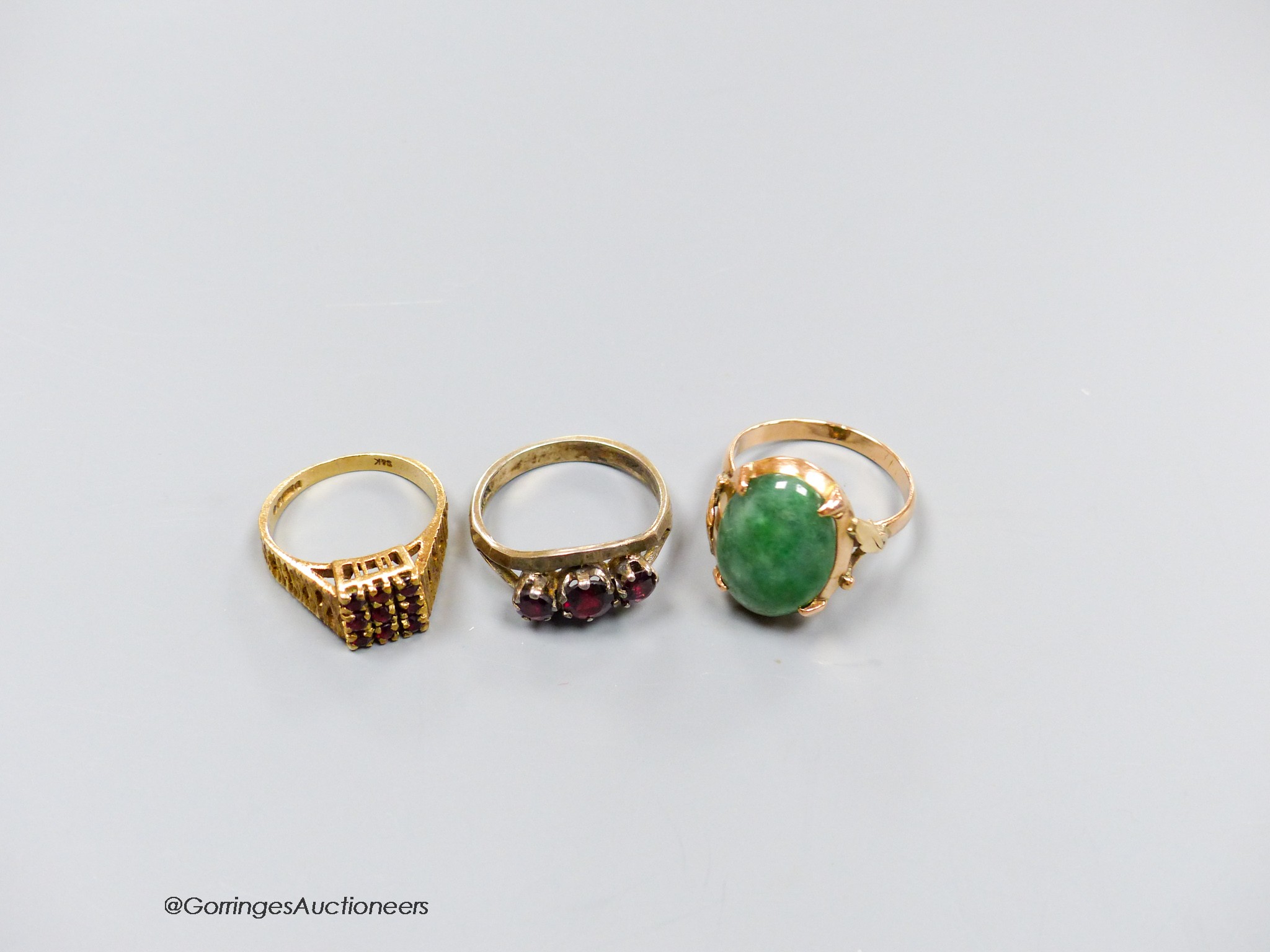 A 9ct gold and garnet cluster ring, a similar white metal ring and a yellow metal and jadeite - Image 2 of 2