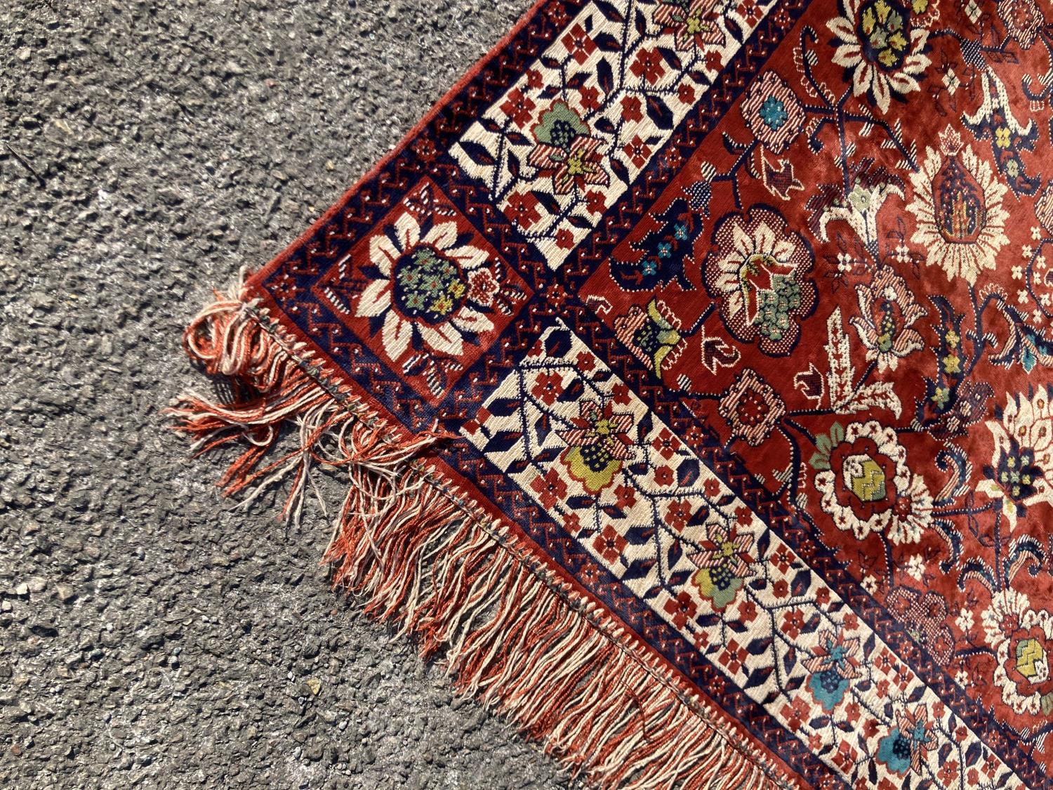 A large embroidered silk rug with a claret red ground interspersed with symmetrical foliate - Image 2 of 5