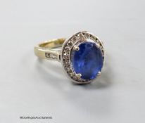 A modern 750 yellow metal, tanzanite and diamond chip oval cluster ring, size P, gross weight 9