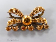 An early 20th century yellow metal and citrine cluster set ribbon bow brooch, with closed back