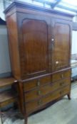 A George IV mahogany linen press, with a pair of hinged panelled doors over two short and two long