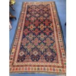 A Caucasian blue ground rug, woven with hooked lozenges, 288 x 152cm