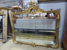 A Victorian style gilt framed wall mirror with pierced surmount and scrolling foliate border, W.