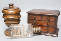 A Victorian mahogany 'chest of drawers' money bank, a turned wood bowl and cover and a small ship