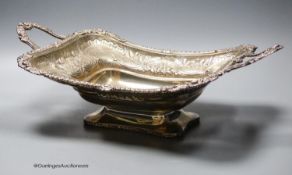A late George III silver two handled bread dish, embossed with foliate scroll decoration, by