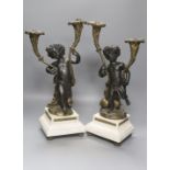 After Clodion. A pair of bronze cherub candelabra on marble bases, converted to lamps, height 42cm