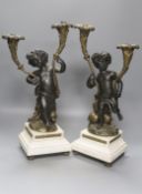 After Clodion. A pair of bronze cherub candelabra on marble bases, converted to lamps, height 42cm