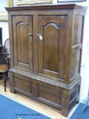An early 18th century oak cupboard fitted a pair of arched fielded panelled doors, width 130cm,