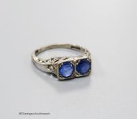 A 1920's white metal (stamped 18ct & plat) and two stone sapphire set ring with carved and single