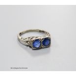 A 1920's white metal (stamped 18ct & plat) and two stone sapphire set ring with carved and single