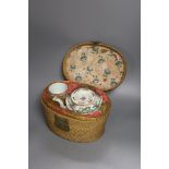 A Chinese teapot and two tea bowls, in carrying basket