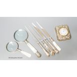 A group of mixed silver to include a travelling timepiece, mother of pearl handled knives, an