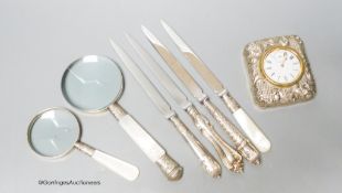 A group of mixed silver to include a travelling timepiece, mother of pearl handled knives, an