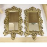 A pair of brass framed wall mirrors with devil and lion mask mounts, width 25cm height 44cm