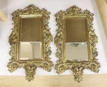 A pair of brass framed wall mirrors with devil and lion mask mounts, width 25cm height 44cm