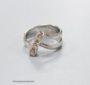 A modern white metal and three stone diamond set twin shank modernist ring, size K, gross weight 5.