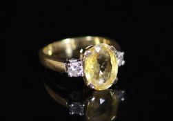 An 18ct gold, yellow sapphire and diamond set three stone ring,the oval cut stone weighing