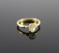 A modern 18ct gold and single stone oval fancy yellow diamond ring, with trapeze cut diamond set