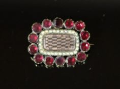 A 19th century gold plated, garnet and seed pearl set mourning brooch,with plaited hair beneath a