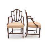 A pair of George III Hepplewhite style mahogany shield back elbow chairs,with foliate carved backs,