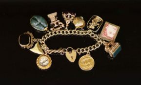 A 1970's 9ct. gold charm bracelet,hung with ten assorted charms, including old telephone, a mounted