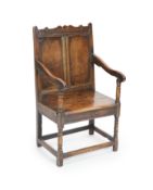 A 17th century oak open armchair,with double panelled back, scroll-carved top rail, solid seat and