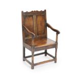 A 17th century oak open armchair,with double panelled back, scroll-carved top rail, solid seat and