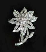 A white gold and diamond encrusted flower brooch,set with round and baguette cut diamonds, the