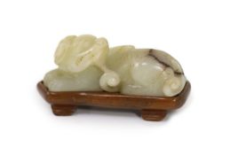 A Chinese pale celadon and brown jade figure of a lion-dog, 18th/19th century,in recumbent pose,