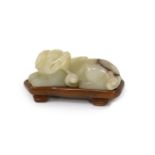 A Chinese pale celadon and brown jade figure of a lion-dog, 18th/19th century,in recumbent pose,