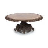 A 19th-century Ceylonese rosewood centre table,The circular tilt top with carved and pierced folate