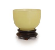 A Chinese yellow hardstone cup, 19th century,5cm diameter, wood stand, rim chip