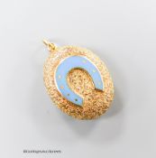A Victorian style textured yellow metal and enamel set oval pendant, with horseshoe motif and